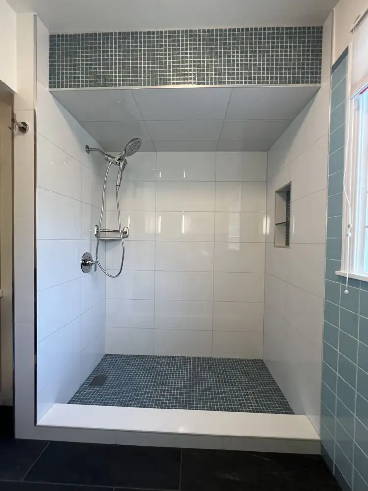 Walk-in shower with large white tile, blue glass mosaic floor and accent band, niche and handheld shower, Northeast Ohio