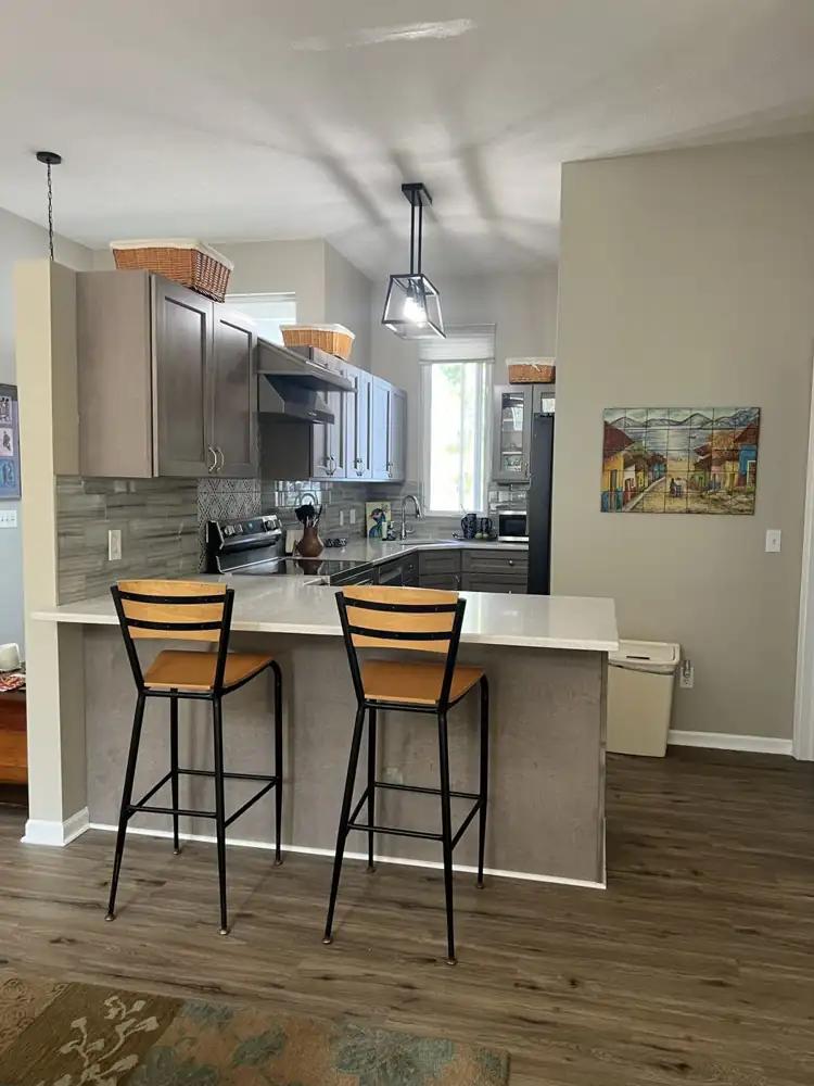 Kitchen with gray stained shaker cabinets, white quartz peninsula, glass tile backsplash and pendant lights, Northeast Ohio