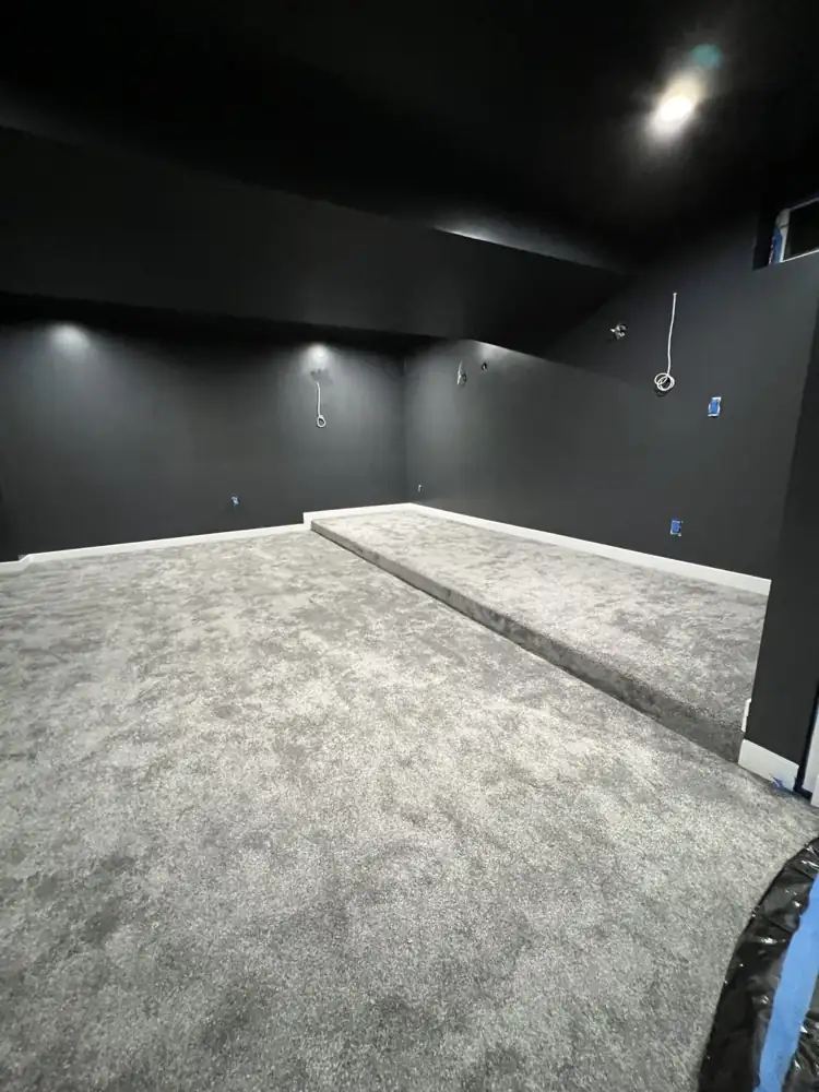 Home theater room painted black with raised carpeted riser during basement finishing, Northeast Ohio