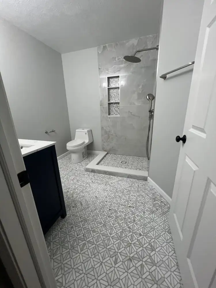 Bathroom with onyx-look porcelain shower wall, marble star mosaic floor, rain head and navy vanity, Northeast Ohio