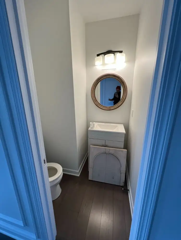 Small powder room with basic vanity and dark wood floor before remodel, Northeast Ohio