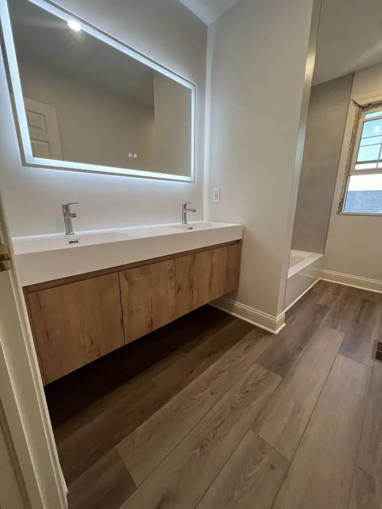 Bathroom with floating oak double vanity, LED mirror and wood-look luxury vinyl plank floor, Northeast Ohio