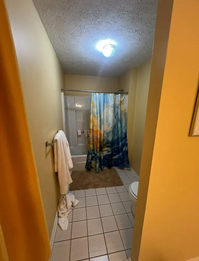 Bathroom with fiberglass tub surround and shower curtain before remodel, Northeast Ohio