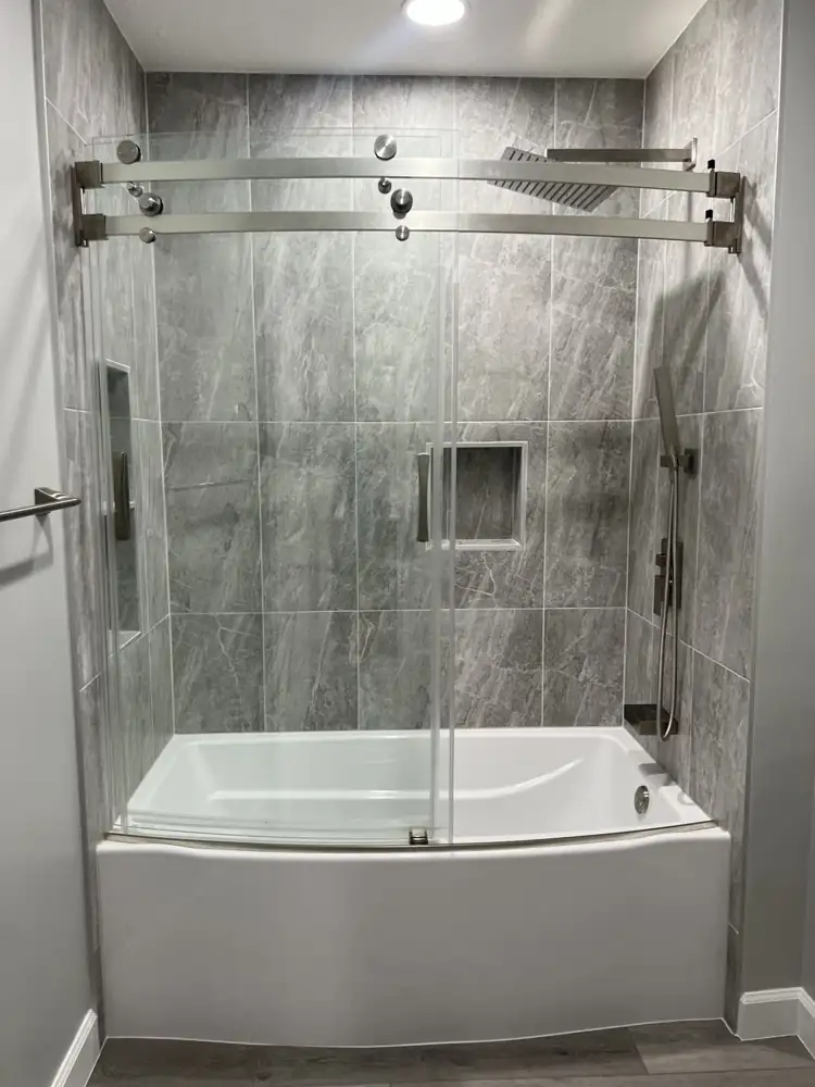 Tub with frameless curved sliding glass door, rain shower, handheld and niche in gray porcelain, Northeast Ohio