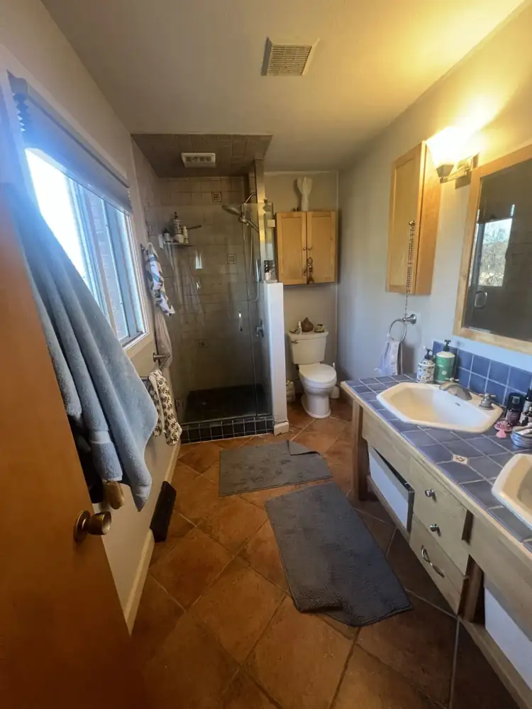 Bathroom with terracotta floor tile, blue tile vanity top and dated tile shower before remodel, Northeast Ohio