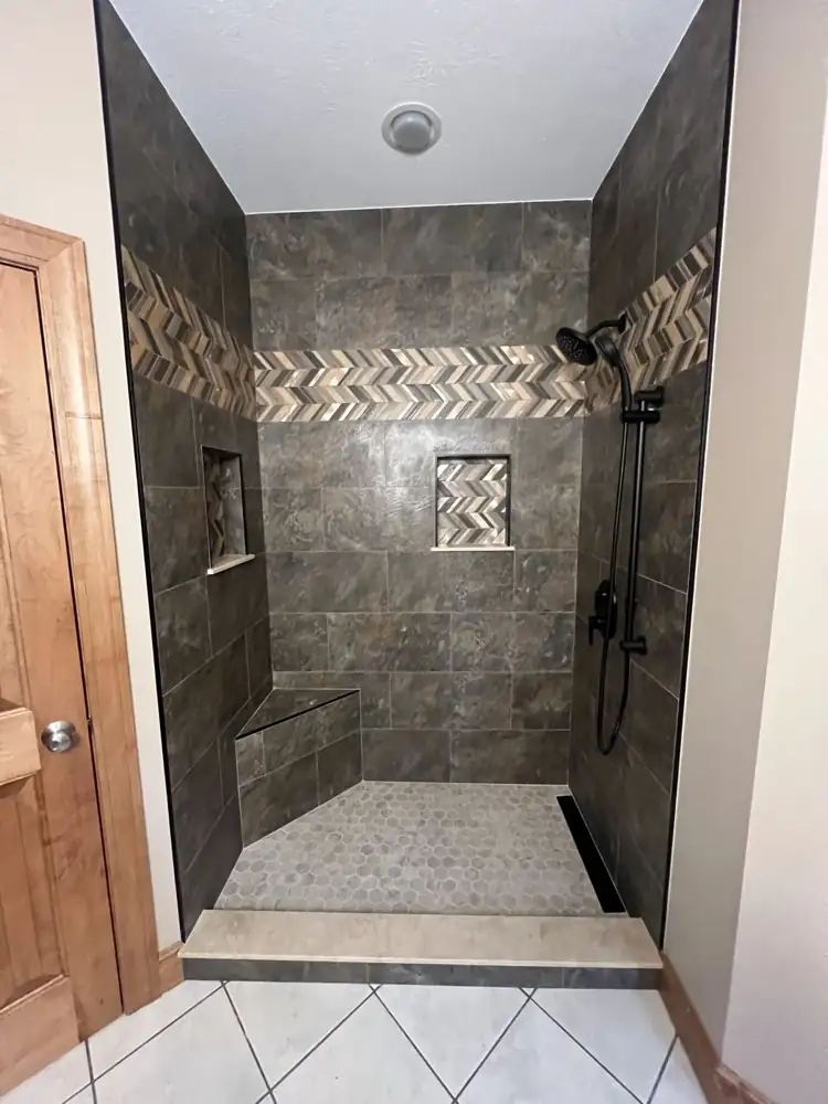 Tub-to-shower conversion with slate-look porcelain, chevron mosaic accent band, corner bench and linear drain, Northeast Ohio