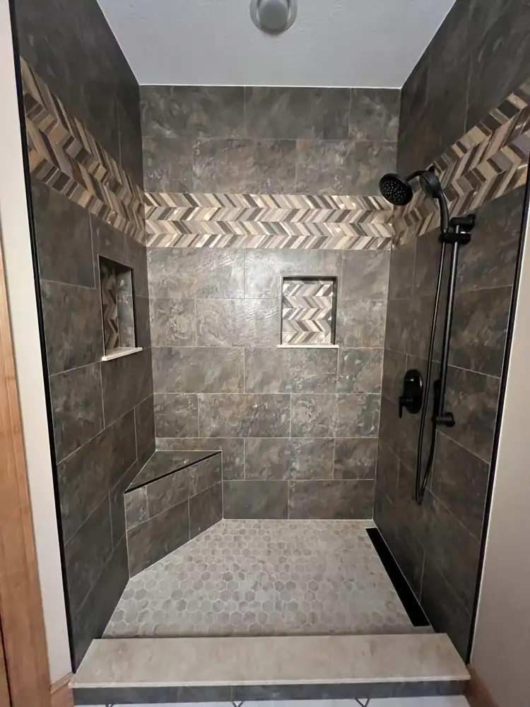 Walk-in shower with dark slate-look tile, two mosaic-lined niches, gray hexagon floor and matte black slide-bar shower, Northeast Ohio