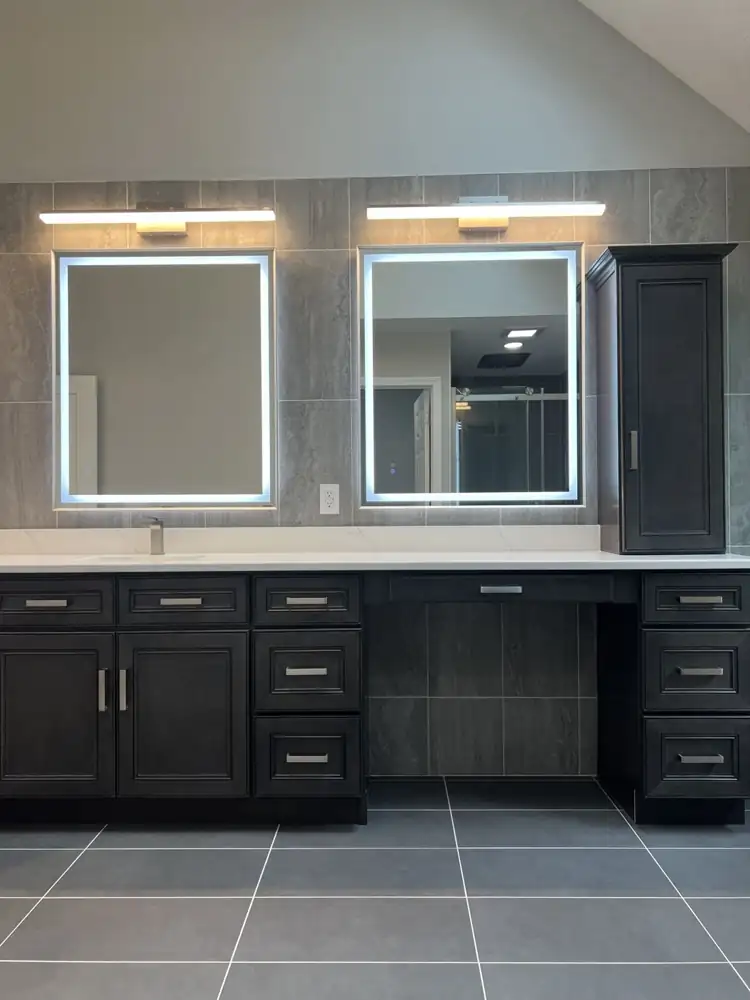 Dark wood vanity with makeup desk, quartz top, tall linen cabinet and LED-lit mirrors on a tiled wall, Northeast Ohio