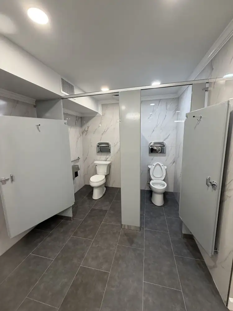Renovated commercial restroom with marble-look porcelain walls, charcoal floor tile, new partitions and toilets, Northeast Ohio