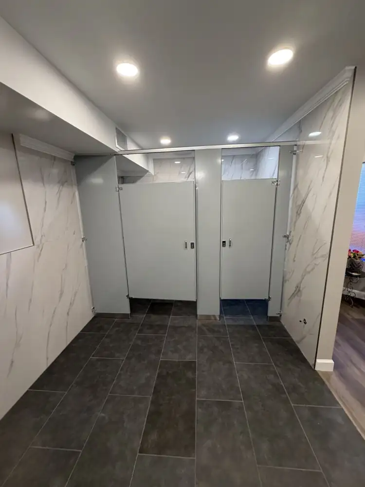 Restroom with new gray toilet partitions, marble-look wall panels and recessed lighting, Northeast Ohio