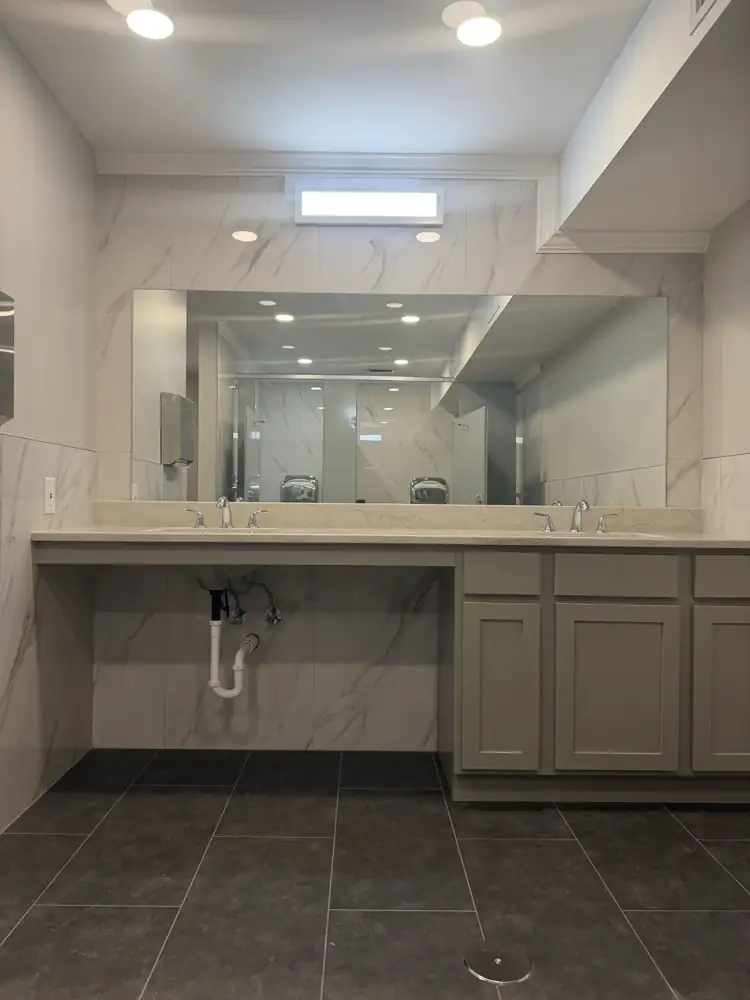 ADA-accessible vanity with quartz top, two sinks, full-width mirror and marble-look tile walls, Northeast Ohio
