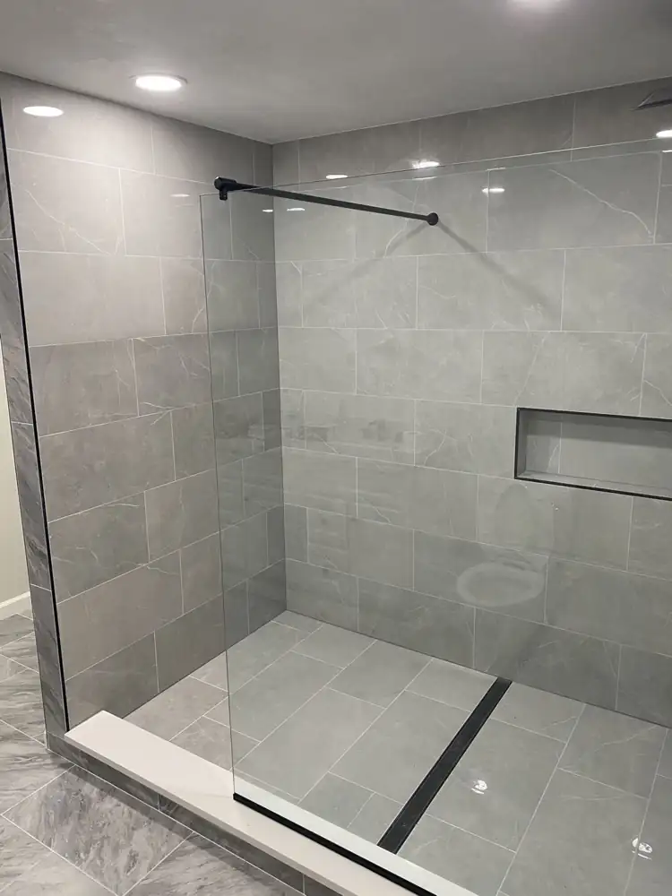 Gray porcelain walk-in shower with frameless glass panel and black linear drain, Northeast Ohio