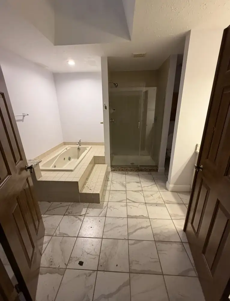 Primary bathroom with tiled jetted-tub platform and beige tile shower before remodel, North Royalton, Ohio