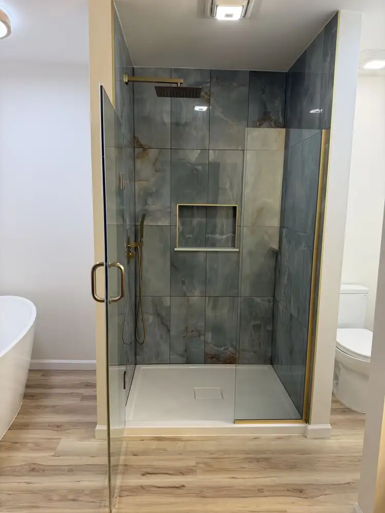 Blue-green onyx-look porcelain shower with brushed gold rain head, handheld, gold-trimmed niche and frameless glass door, Ohio