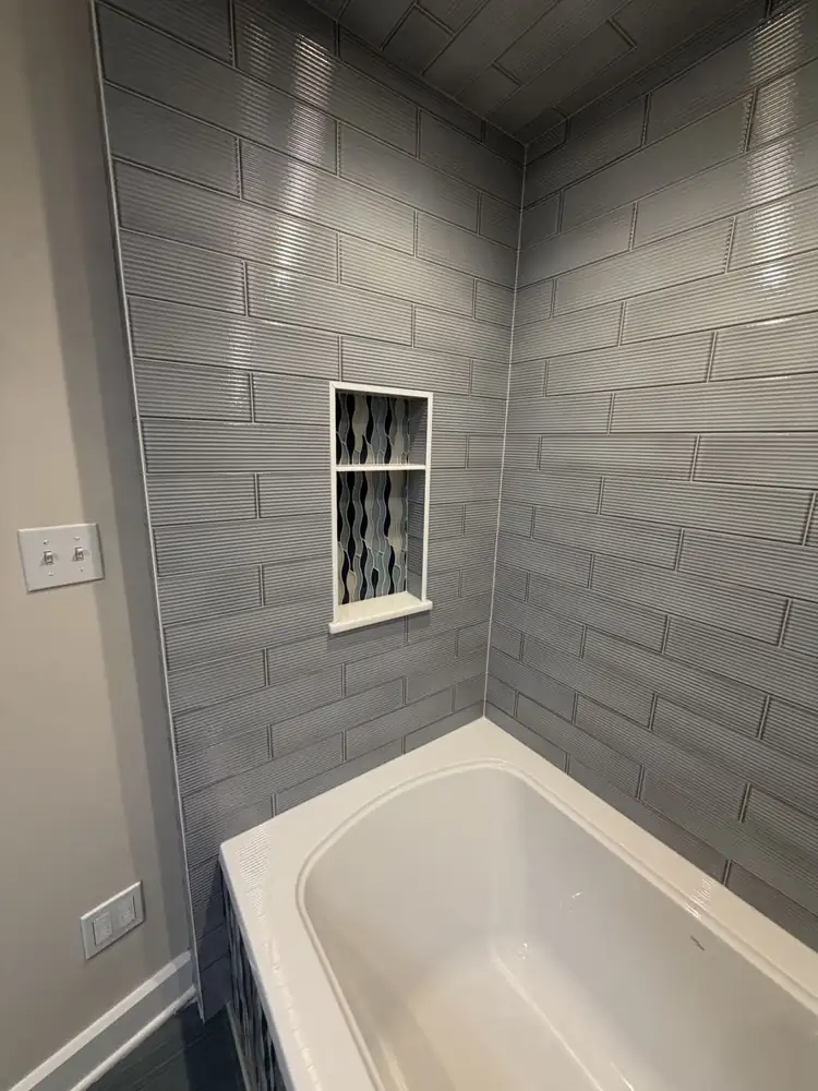 Shower niche lined with blue wave mosaic tile