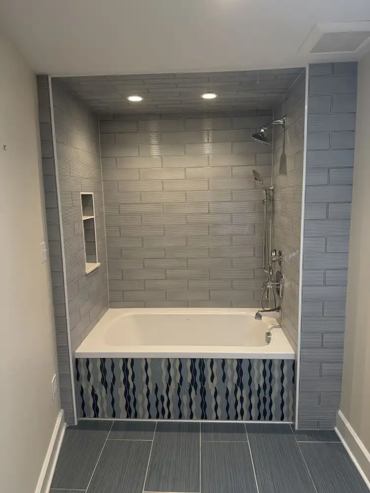 Another view: Soaking tub with textured gray tile walls and ceiling and blue wave mosaic tub front, Rocky River, Ohio