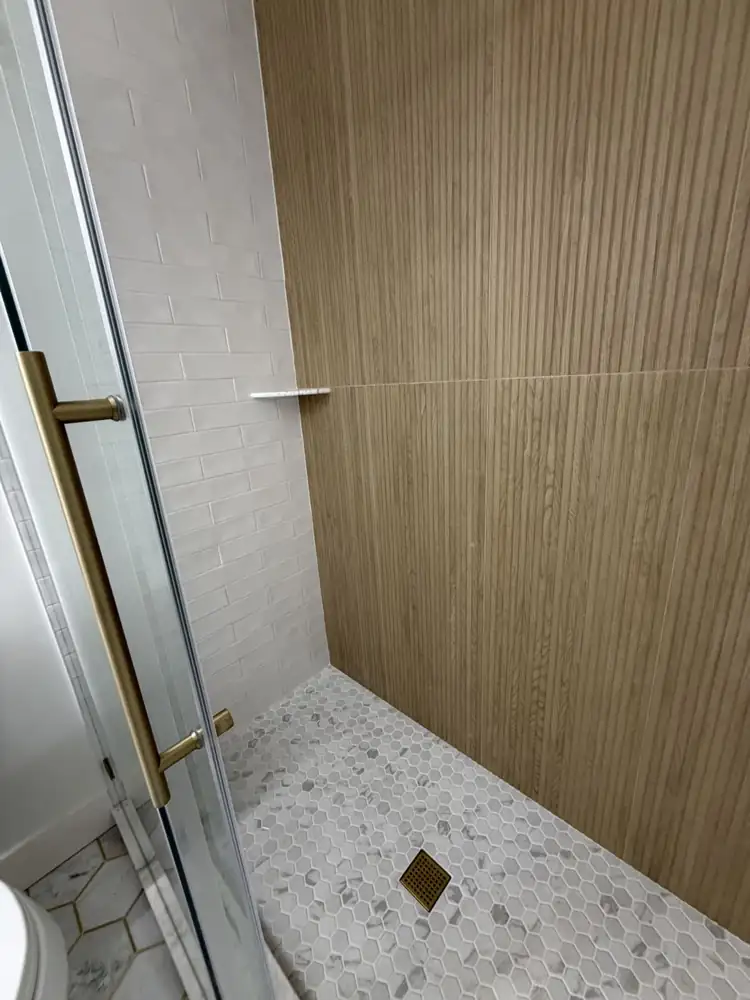 Walk-in shower with fluted wood-look porcelain accent wall, white subway tile and marble hex mosaic floor, Ohio