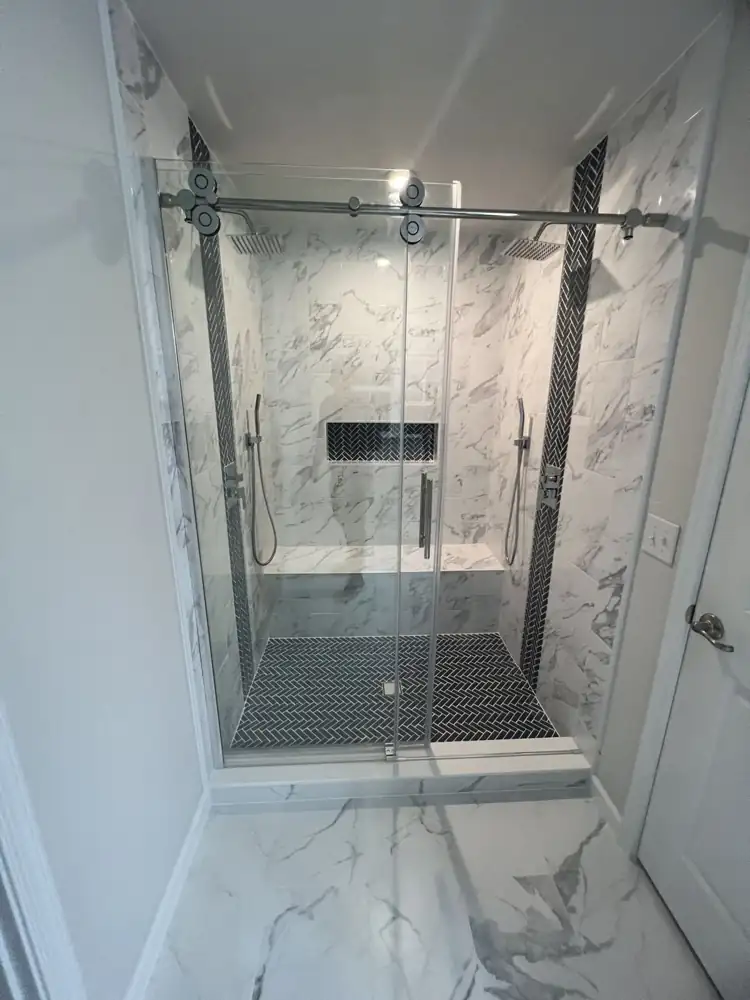 Double shower with marble-look tile, navy herringbone accents, bench and sliding glass door, Streetsboro, Ohio