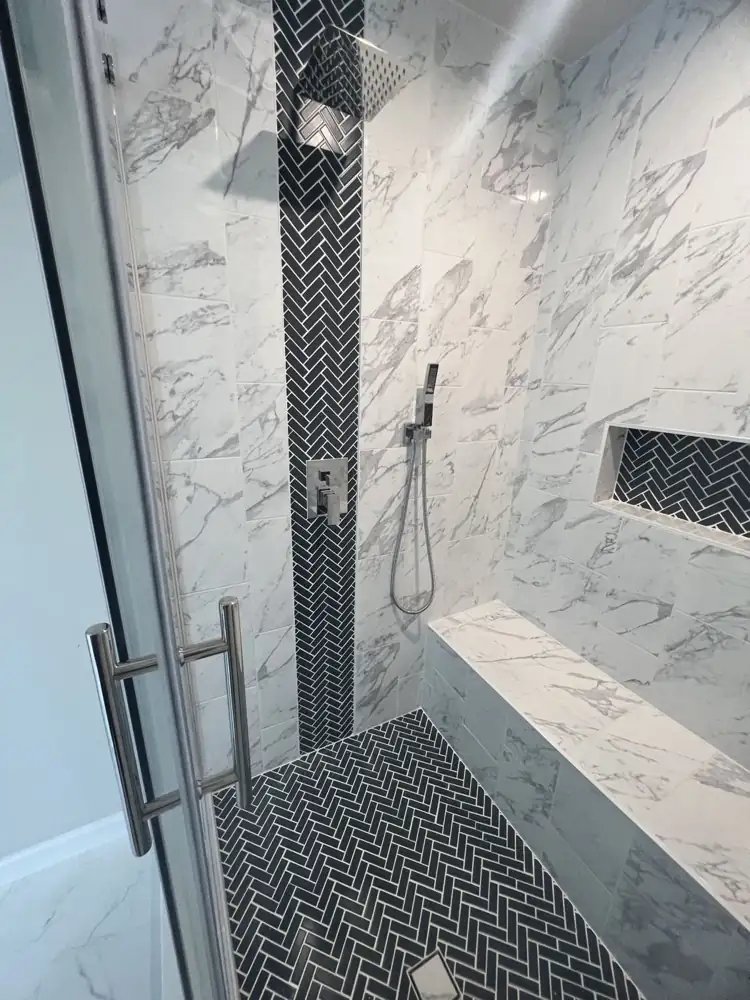 Navy herringbone tile accent stripe, niche and floor in a marble-look shower, Ohio