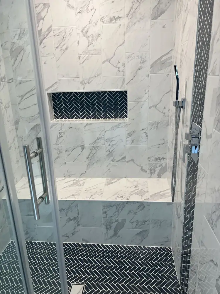Another view: Double shower with marble-look tile, navy herringbone accents, bench and sliding glass door, Streetsboro, Ohio