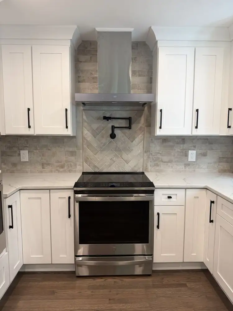 Herringbone tile accent and pot filler behind the range