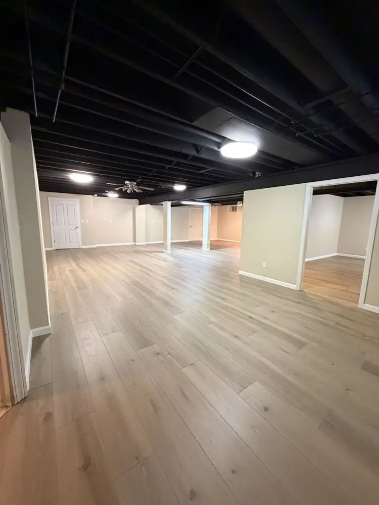 Another view: Finished basement with black painted open ceiling, drywall, wrapped posts and luxury vinyl plank floor, Solon, Ohio