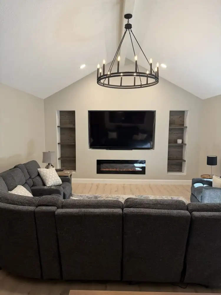 Family room with vaulted ceiling, iron chandelier, built-in TV niche, electric fireplace, reclaimed-wood shelving niches and light plank floors, Solon, Ohio