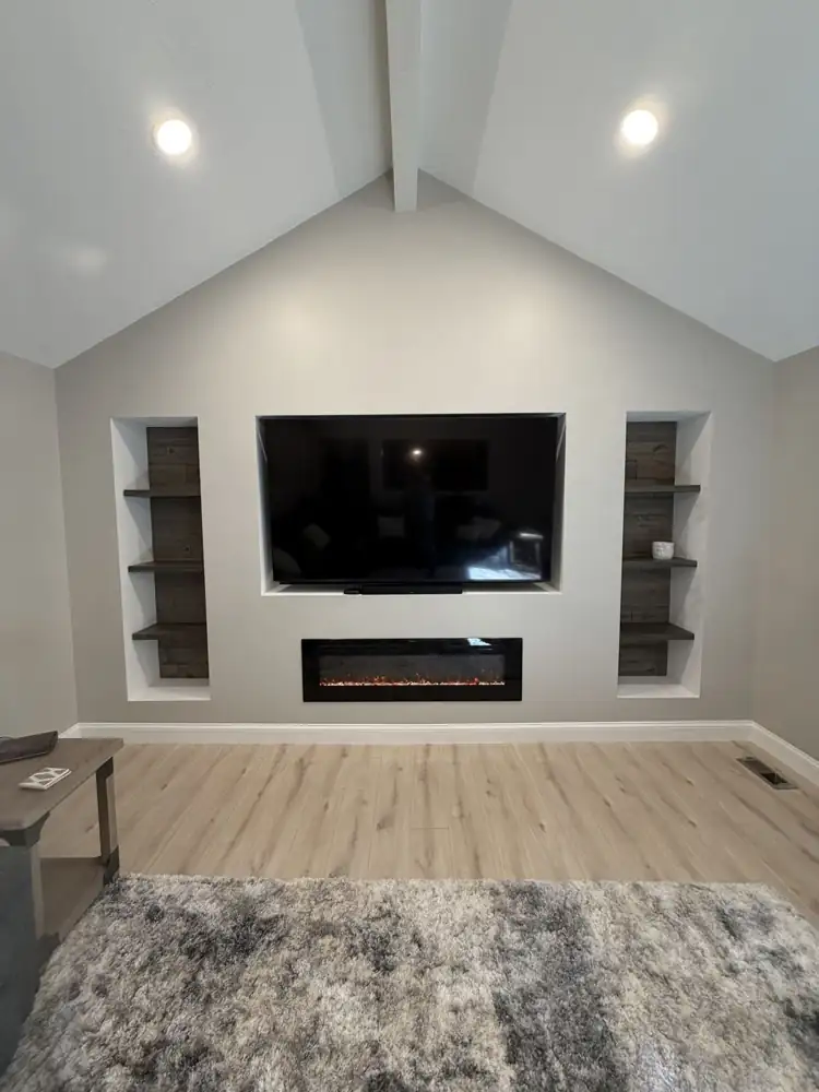 Built-in media wall with recessed TV niche, linear electric fireplace and reclaimed-wood shelf niches under a vaulted ceiling, Ohio