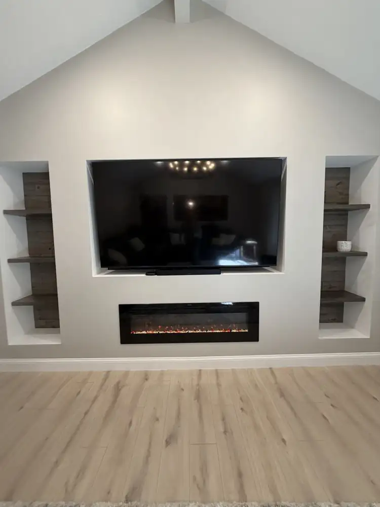 Another view: Family room with vaulted ceiling, iron chandelier, built-in TV niche, electric fireplace, reclaimed-wood shelving niches and light plank floors, Solon, Ohio