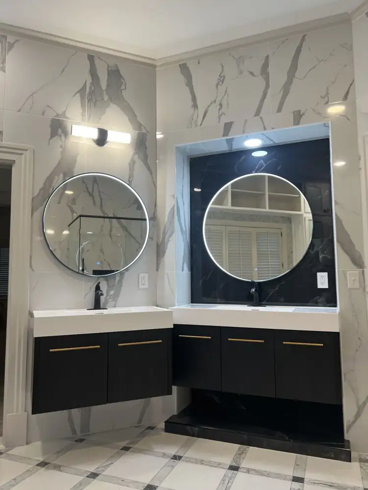 Two floating vanities with round lighted mirrors and a black marble-look niche, Strongsville