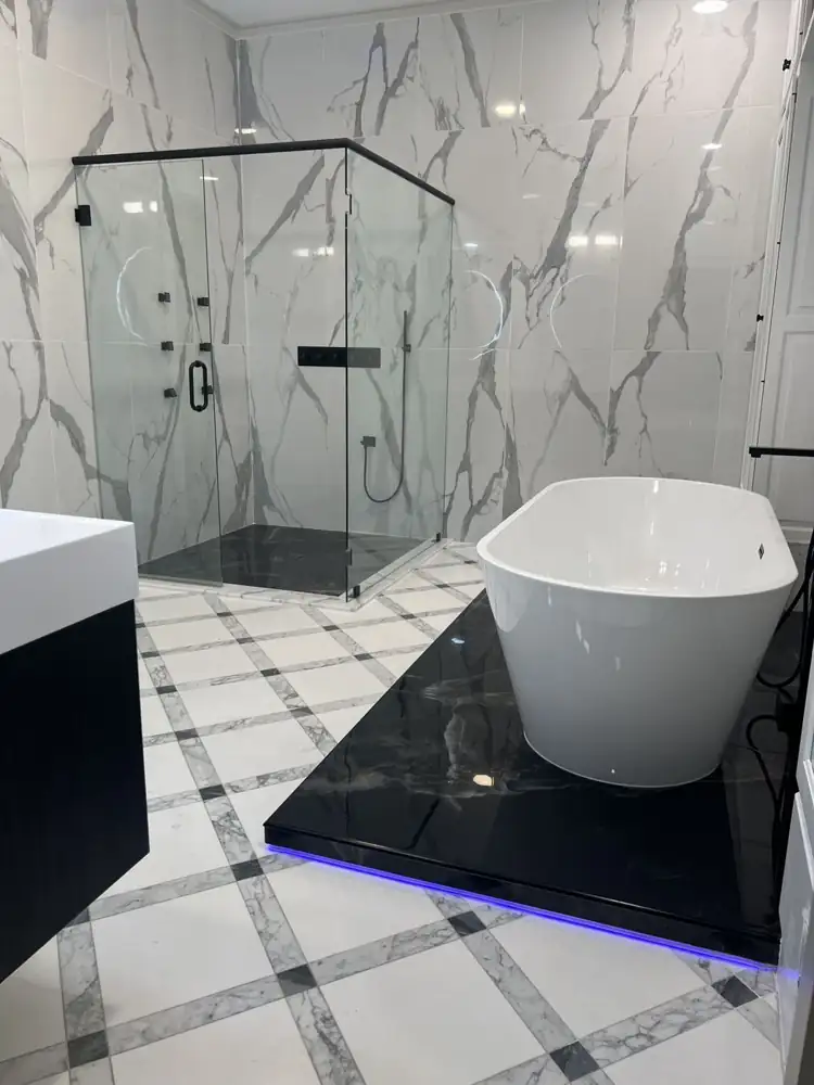 Another view: Primary bathroom with glass shower, LED ceiling rain head, body jets, black marble-look floor and freestanding tub on a lit platform, Strongsville, Ohio