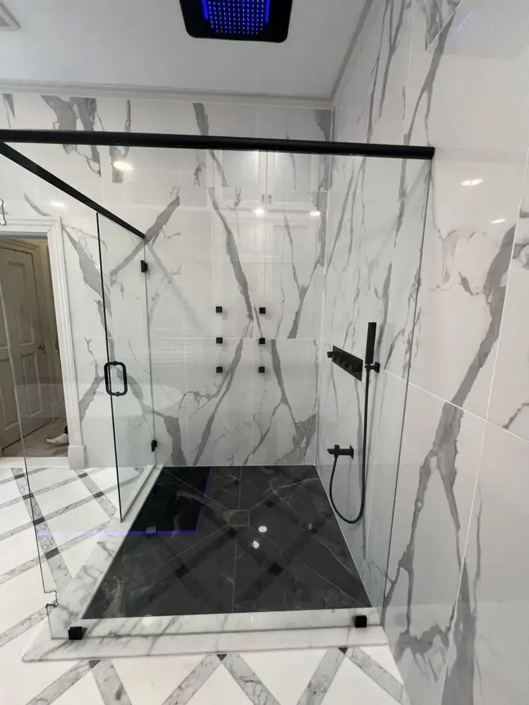 Another view: Primary bathroom with glass shower, LED ceiling rain head, body jets, black marble-look floor and freestanding tub on a lit platform, Strongsville, Ohio