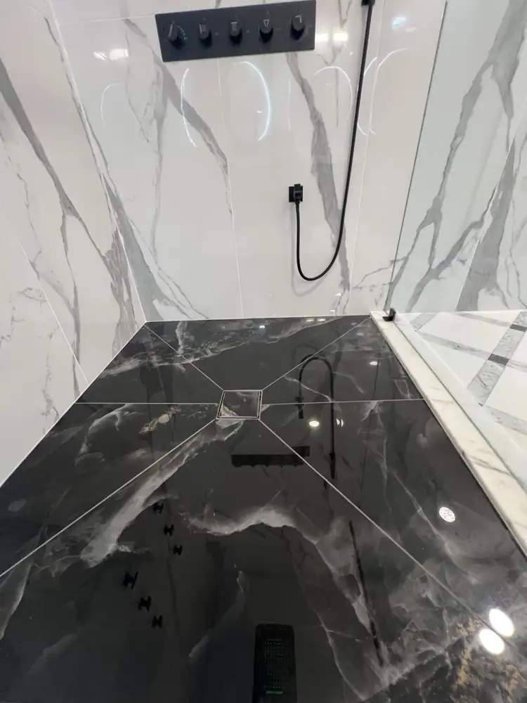 Another view: Primary bathroom with glass shower, LED ceiling rain head, body jets, black marble-look floor and freestanding tub on a lit platform, Strongsville, Ohio