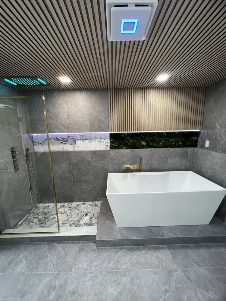 Primary bathroom with freestanding tub on tiled platform, moss wall and wood slat ceiling, Twinsburg