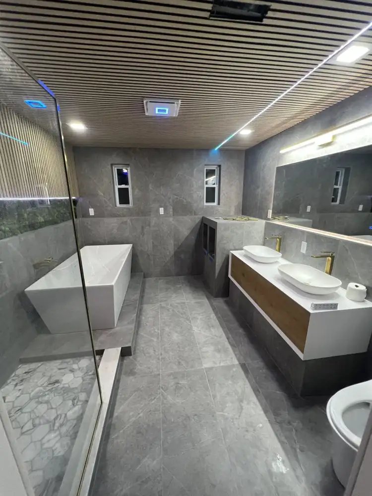 Primary bathroom with large-format gray porcelain tile and wood slat ceiling